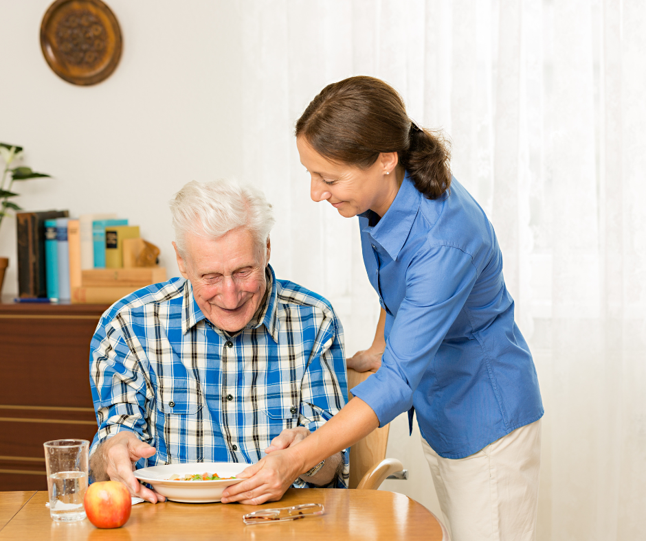 caregiver helping elderly man with meal time